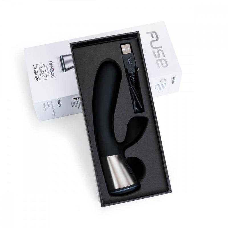 A top-down image shows the OhMiBod Fuse in black laying inside of its packaging box. It's shown with the charging cable. | Kinkly Shop
