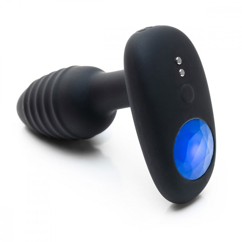 Angled image shows a close-up of the base of the OhMiBod Lumen. You can see the magnetic charging ports, the button that controls the vibrations, and the gem-like area that functions as the light for this lightshow butt plug. | Kinkly Shop