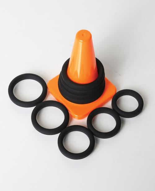 Top-down view of the Perfect Fit Play Zone Cock Ring Sizing Kit. Four of the largest cock rings are looped around the storage cone while the five remaining cock rings are spread out and laid flat on the floor around it. | Kinkly Shop