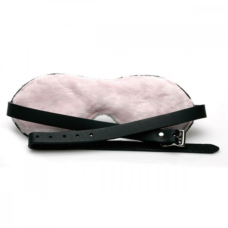 The Sex Kitten Leather Buckle Blindfold up against a white background with the interior pink, faux fur side showing. | Kinkly Shop
