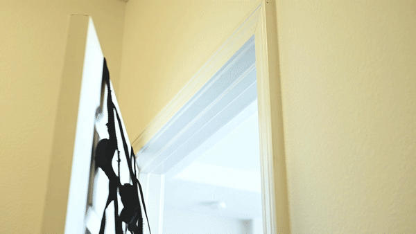 GIF showing how simply the Sportsheets Door Jam Sex Sling Special Edition plus size sex swing sets up on a door. It shows the straps wrapped on top of a door as the door is closed - then a hand tightens the sex sling straps. | Kinkly Shop