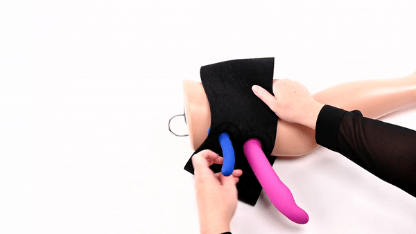 GIF shows a person wrapping the Sportsheets Dual Penetration Thigh Strap-On Harness around a mannequin thigh while the harness has two differently-sized, bright dildos already slid through its two O-rings. | Kinkly Shop