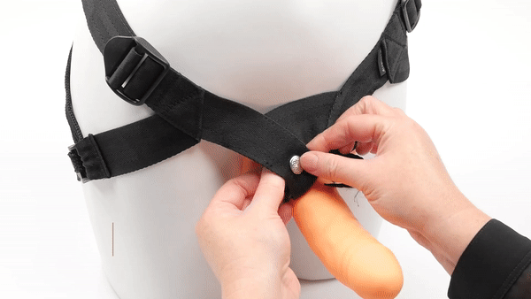 GIF showing the harness being used alongside the included dildo on a mannequin torso. The person's hands are fastening the snaps around the O-rings that hold the dildo in the strap-on harness. The text says "Can be used with other dildos". | Kinkly Shop
