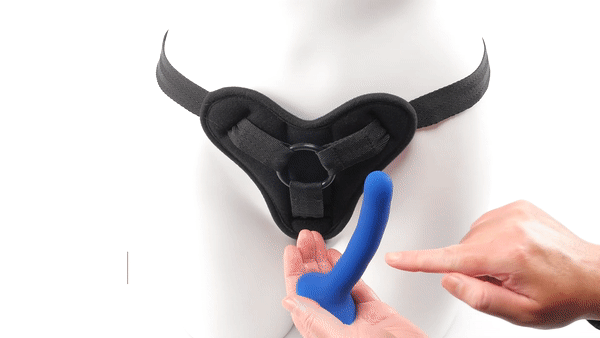 GIF of the Sportsheets New Comer's Kit Special Edition. The harness is being worn around the hips of a mannequin. A hand pulls the O-ring away from the mannequin to insert the included, slender dildo into the harness while the mannequin is wearing the harness. The text on the GIF reads "1.25 Rubber O-Ring. Interchangeable (included)" and "Dildo Included. 5.25" Slim, Silicone." | Kinkly Shop