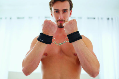 A muscular person presents their forearms straight to the camera. The Sportsheets Soft Wrist Cuffs are wrapped around their wrists and connecting their two arms together. | Kinkly Shop