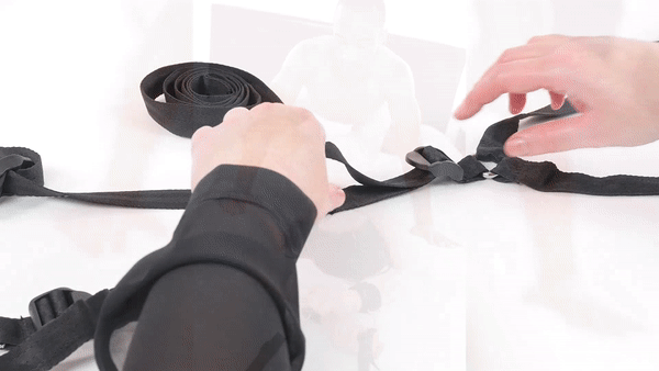 GIF shows a person adjusting the under-the-bed length strap (to fit under multiple bed sizes) in addition to wrapping one of the adjustable, velcro bondage cuffs around their wrist | Kinkly Shop