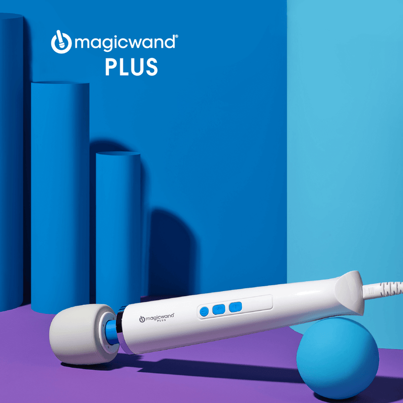 The base of the Vibratex Magic Wand Plus is balancing on a ball while the head of the massager sits on a purple floor. The background is multiple hues of blue, and geometric cylinders are stacked up behind the massager. | Kinkly Shop