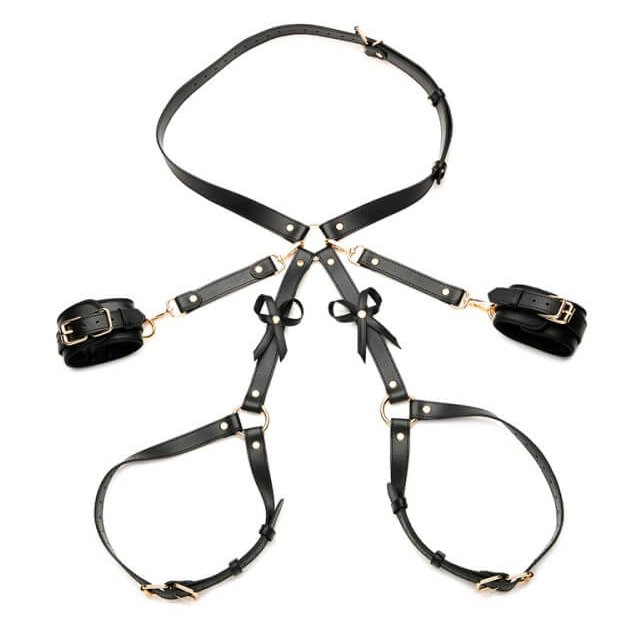 Strict Bondage Harness with Bows in black laid out against a white background. With large loops and the cuffs connected, this lay-flat design makes it easy to see how the harness would wrap around the hips and wrap around both thighs. The cuffs could be attached to the hip's O-ring. | Kinkly Shop