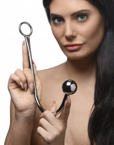 A person is looking straight into the camera while holding the Master Series Stainless Steel Anal Hook with both hands. Perfect as a size reference, this image shows that the anal hook is much longer than the length of a single hand (fingertip to base of palm) and closer to the length of two hands. | Kinkly Shop