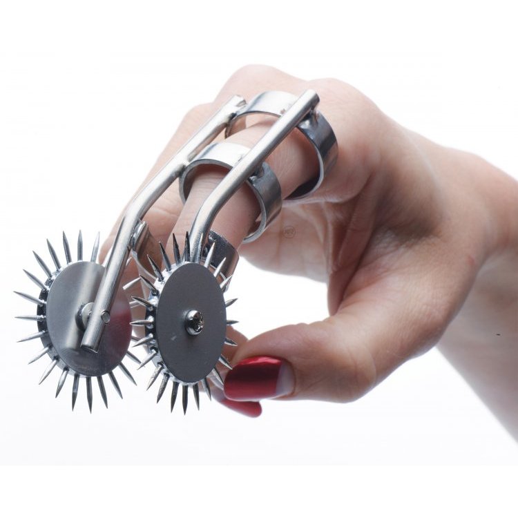 A finger is slid inside of the XR Brands Spikes Double Finger Pinwheel. The two wheels of the toy extend beyond the finger's reach on either side of the finger. | Kinkly Shop